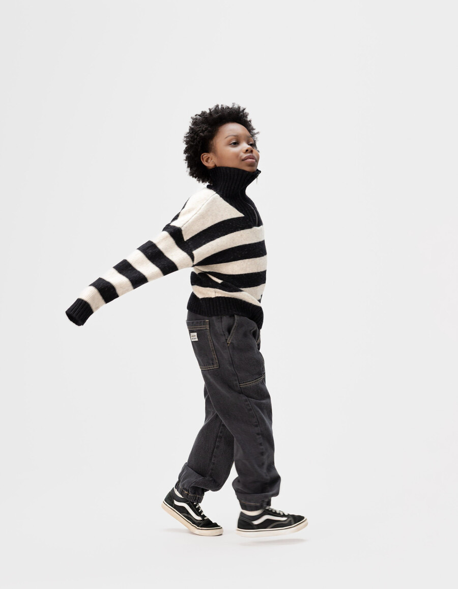suéter de punto negro con cuello con cremallera y rayas beige para niño